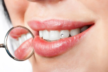 dental mouth mirror near healthy white woman teeth with precious stone on it